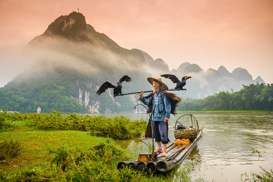 Hombre pescador en el rio con fondo en las montañas de Yangshuo
