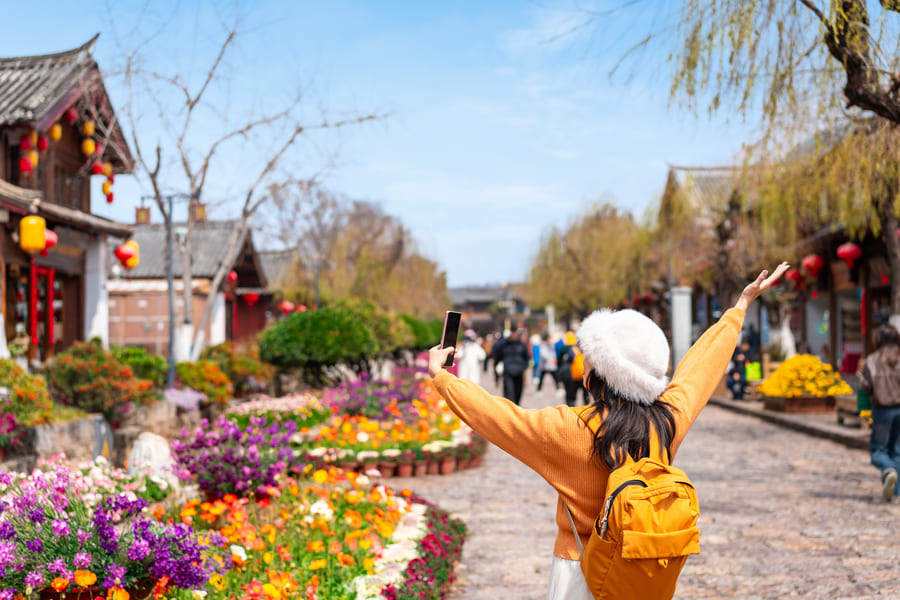 mujer con gorro blanco y chamarra amarilla paseando por yunnan